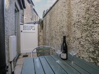 a bottle of wine sitting on a wooden table with two glasses at Drapers Cottage in Grange Over Sands