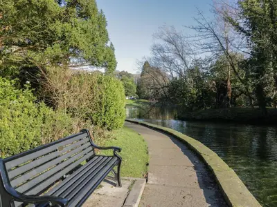 a park bench sitting next to a river at Drapers Cottage in Grange Over Sands
