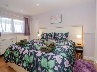 a bedroom with a large bed with towels on it at Drapers Cottage in Grange Over Sands