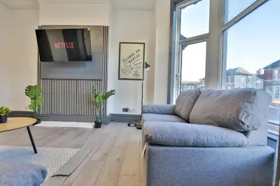 a living room with a blue couch and a tv at Chesterfield House, Blackpool, Free Parking in Blackpool
