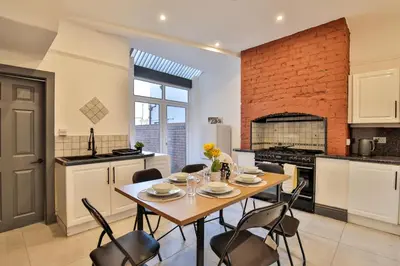 a kitchen with a table and chairs and a brick wall at Chesterfield House, Blackpool, Free Parking in Blackpool