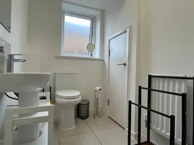 a bathroom with a toilet and a sink and a window at Two Bedroom House with Free Parking in Liverpool