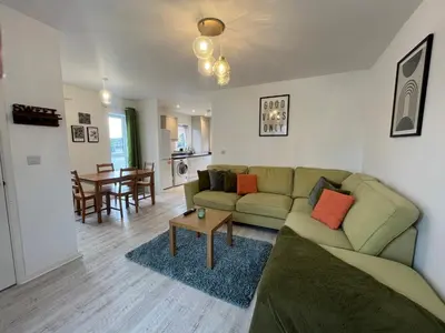a living room with a green couch and a table at Two Bedroom House with Free Parking in Liverpool