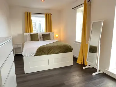 a bedroom with a bed with yellow curtains and a mirror at Two Bedroom House with Free Parking in Liverpool