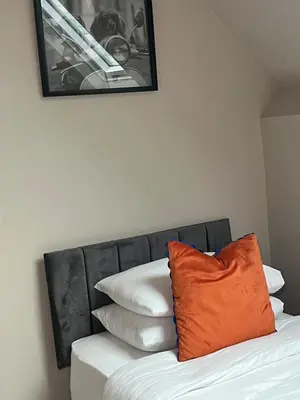 an orange pillow sitting on top of a bed with pillows at 2BR Cosy Wallasey Stay Near Liverpool WiFi Parking in Wallasey