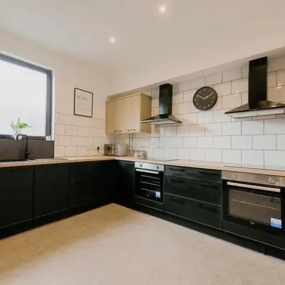 a kitchen with black cabinets and a clock on the wall at Cosy New Brighton Room for Rent in New Brighton