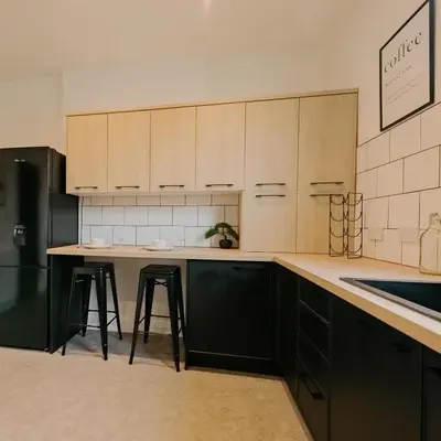 a kitchen with wooden cabinets and a island with bar stools at Cosy New Brighton Room for Rent in New Brighton
