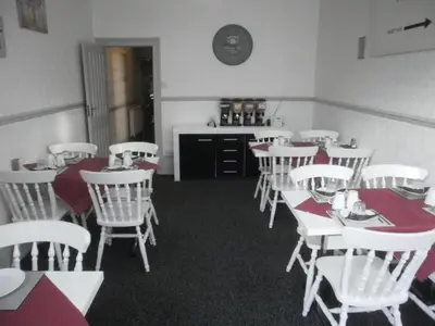 a dining room with white tables and white chairs at Marsden B&B in Blackpool