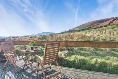 two chairs and a table with flowers on a deck at 1 Bed in Newton In Bowland oc-h34064 in Newton