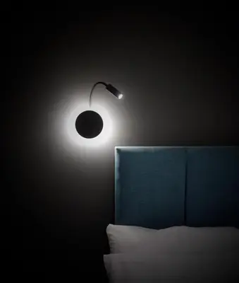 a light fixture on a wall next to a bed at The Ferny Hoolet in Caton