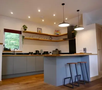a kitchen with a counter and two stools at The Ferny Hoolet in Caton