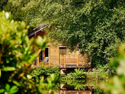 a log cabin with a porch on a river at The Ferny Hoolet in Caton