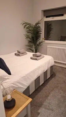 a white bed with two towels on top of it at Victorian Suites Apartment in Southport