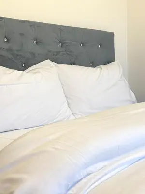 a bed with white pillows and a black headboard at Wigan 2-Bedroom Modern house - Cozy & Relaxing Stay in Bickershaw