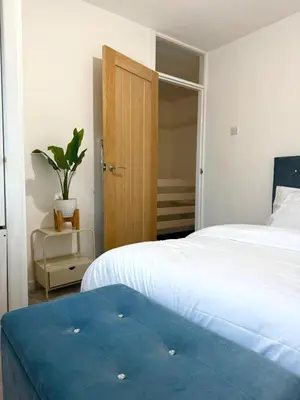 a bedroom with two beds and a door with a potted plant at Wigan 2-Bedroom Modern house - Cozy & Relaxing Stay in Bickershaw