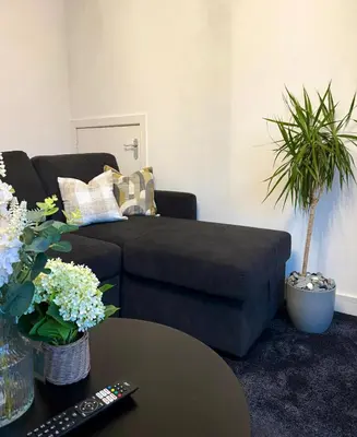 a living room with a couch and a table at Wigan 2-Bedroom Modern house - Cozy & Relaxing Stay in Bickershaw