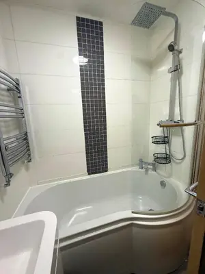 a white bath tub with a black tile shower at Wigan 2-Bedroom Modern house - Cozy & Relaxing Stay in Bickershaw
