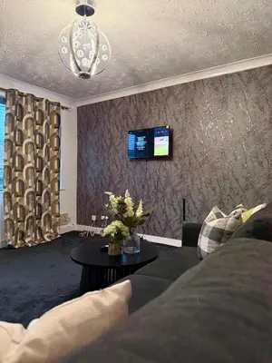 a living room with a couch and a tv on a wall at Wigan 2-Bedroom Modern house - Cozy & Relaxing Stay in Bickershaw