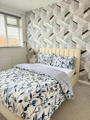 a bedroom with a bed and a geometric accent wall at Wigan 2-Bedroom Modern house - Cozy & Relaxing Stay in Bickershaw