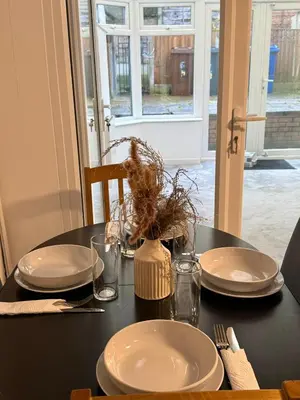 a black table with plates and utensils on it at Wigan 2-Bedroom Modern house - Cozy & Relaxing Stay in Bickershaw