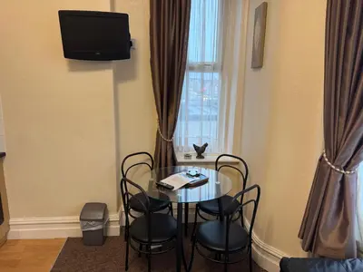 a dining room table with chairs and a window at Woodfield Lodge Apartments in Blackpool