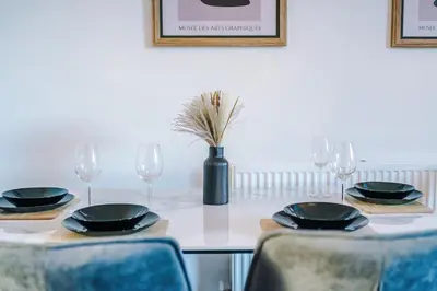 a table with chairs and glasses and a vase with a plant at Presented by LTJ PrimeKey Properties - NEW! 4 Bed plus Sofa Bed, Perfect for Contractors in Saint Helens