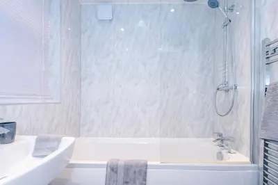 a white bathroom with a tub and a sink at Presented by LTJ PrimeKey Properties - NEW! 4 Bed plus Sofa Bed, Perfect for Contractors in Saint Helens