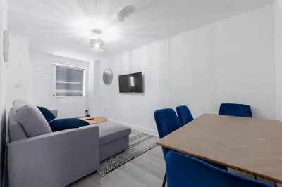 a living room with a table and blue chairs at Modern Family Home Near Liverpool City in Wallasey