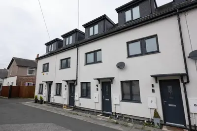 a white house with black doors and windows at Modern Family Home Near Liverpool City in Wallasey