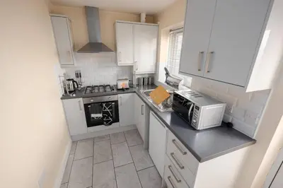 a small kitchen with white cabinets and a microwave at Modern Family Home Near Liverpool City in Wallasey