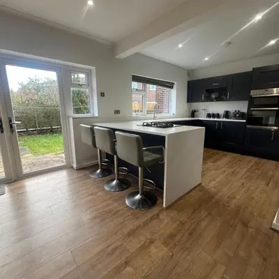 a kitchen with a large island with bar stools at Stylish family home with cinema-style lounge near Blackpool in Blackpool