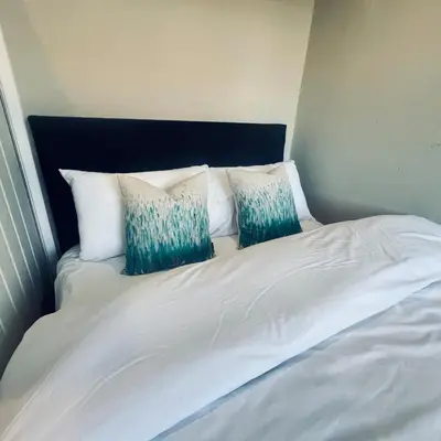 a white bed with three pillows on top of it at Stylish family home with cinema-style lounge near Blackpool in Blackpool