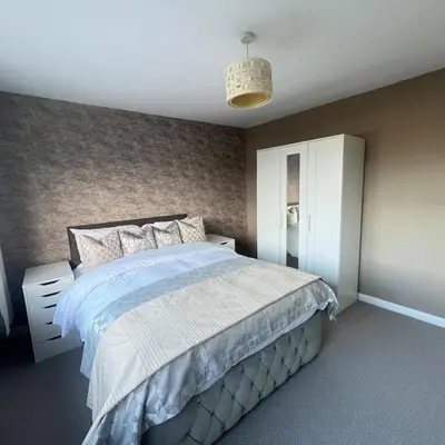 a bedroom with a large bed and a white cabinet at Stylish family home with cinema-style lounge near Blackpool in Blackpool