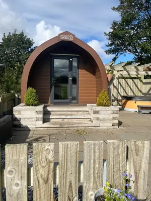 a small house with a wooden fence in front of it at Mill House Farm Pods - Lapwing Lodge in Pilling