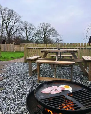 a picnic table and a grill with a picnic table and benches at Mill House Farm Pods - Lapwing Lodge in Pilling