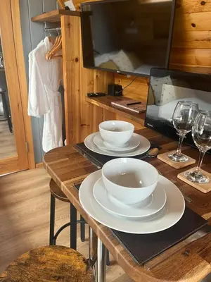a wooden table with two white bowls and wine glasses at Mill House Farm Pods - Lapwing Lodge in Pilling