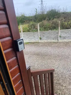 a wooden door with a latch on a door with a fence at Kingfisher Cosy Lakeside Lodge in Carnforth