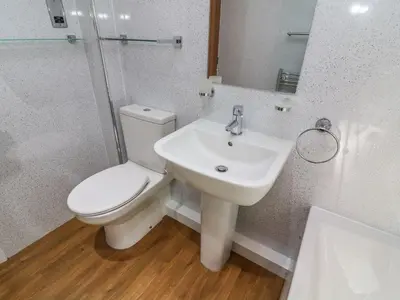 a white bathroom with a toilet and a sink at The Coach House in Carnforth