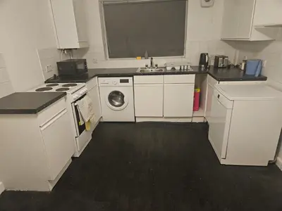 a white kitchen with a sink and a washing machine at Relaxing and Comfort in Preston