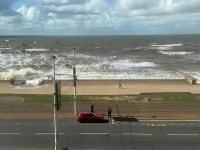 a red car parked on a road near the ocean at Sea View Camper Van in Blackpool