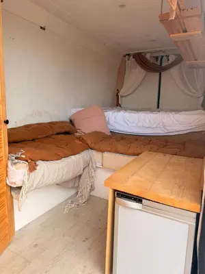 two beds in a small room with a table at Sea View Camper Van in Blackpool