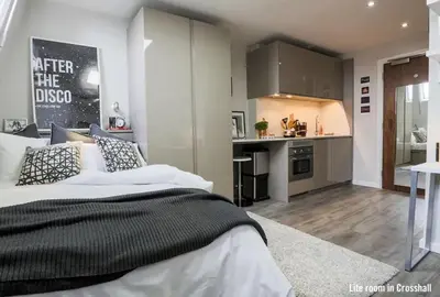 a bedroom with a large bed and a kitchen at For Students Only Cozy Stays at Crosshall Street in Liverpool