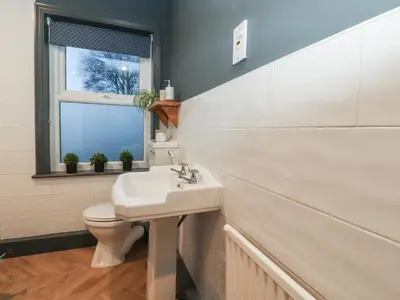 a bathroom with a sink and a toilet and a window at Levenside in Preston