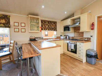 a kitchen with white cabinets and a wooden counter top at Kingfisher Lodge - Arnside 14 in Carnforth