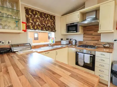 a kitchen with white cabinets and a wooden floor at Kingfisher Lodge - Arnside 14 in Carnforth
