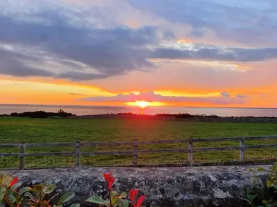 a sunset over a field with a fence at Retreat By The Seaside in Heysham