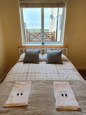a bedroom with a bed with a large window at Retreat By The Seaside in Heysham
