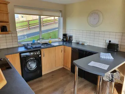 a kitchen with a sink and a washing machine at Retreat By The Seaside in Heysham