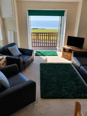 a living room with couches and a television and a balcony at Retreat By The Seaside in Heysham