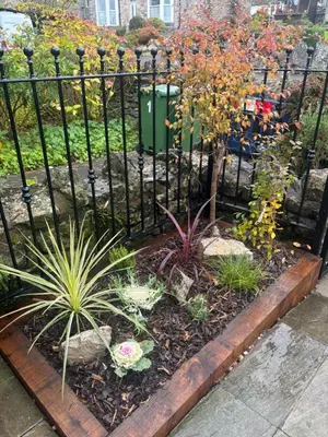 a garden with a black fence and some plants at Grayrigge Croft Cottage in Grange Over Sands